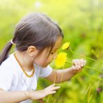 Criança cheirando flor